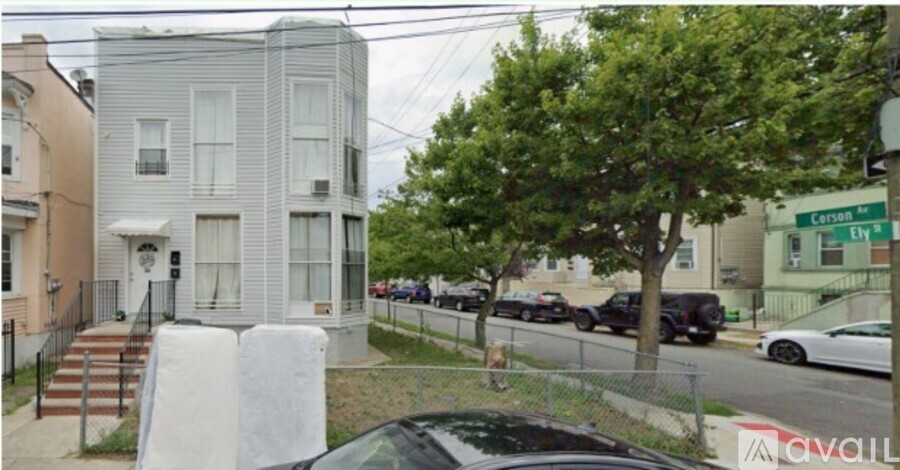 A grey house with two windows, one of which has a string of lights.