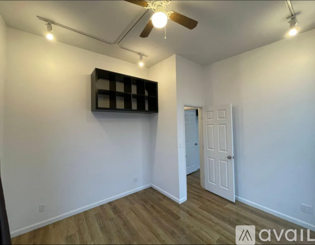 A room with a ceiling fan and a door leading to another room.