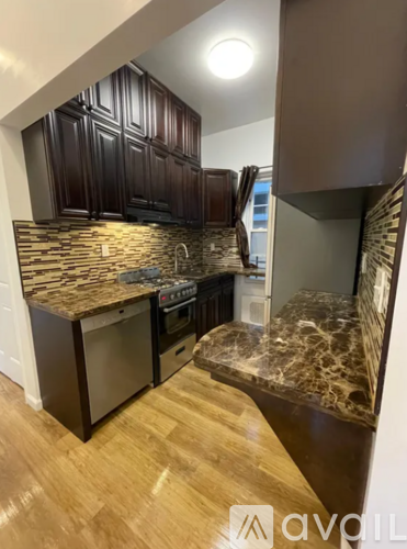 A kitchen with dark wood cabinets and a marble countertop.