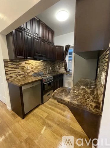 A kitchen with dark wood cabinets and a marble countertop.