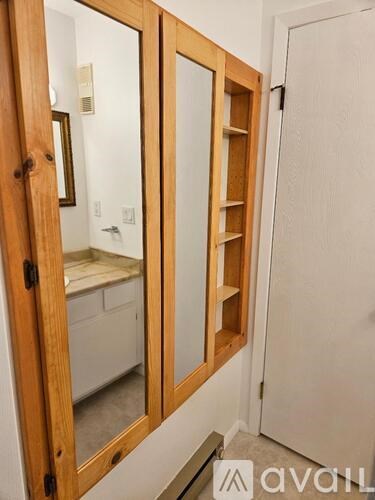 A wooden medicine cabinet with a mirror and a shelf is in the image.