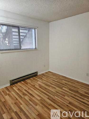 A room with wooden flooring and a window with blinds.