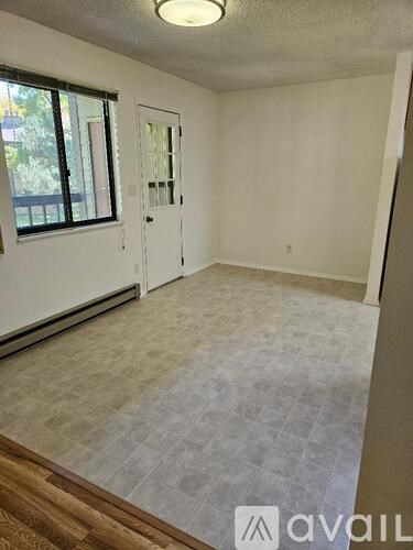 A room with a tiled floor and a window with a view of trees.