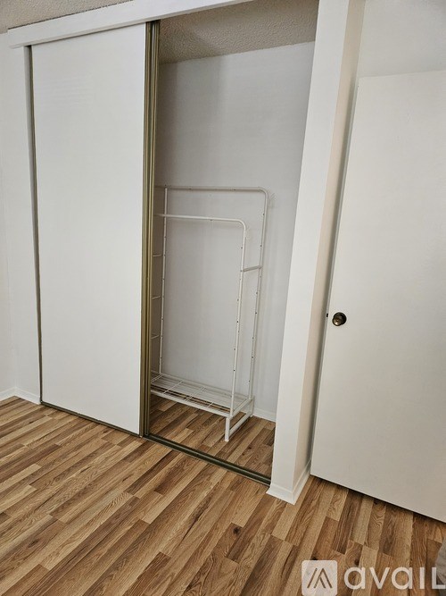 A white closet with a mirrored door is open.