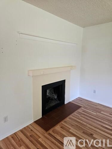 A room with a fireplace and wooden flooring.