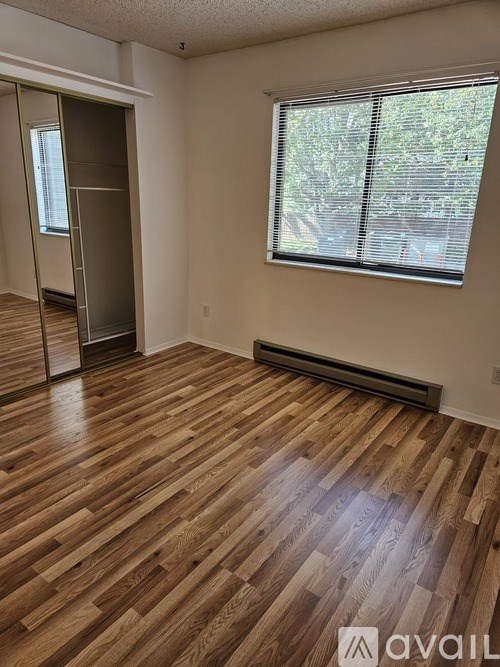 A room with wooden flooring and a window with blinds.