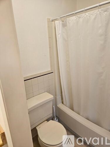 A white toilet in a bathroom with a white shower curtain.