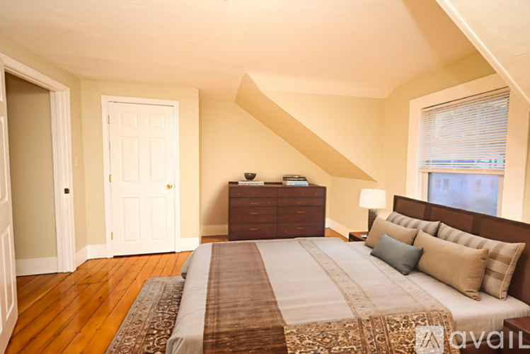 A bedroom with a large bed and a wooden floor.