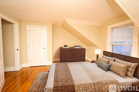 A bedroom with a large bed and a wooden floor.