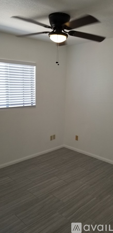 A room with a ceiling fan and a window with blinds.