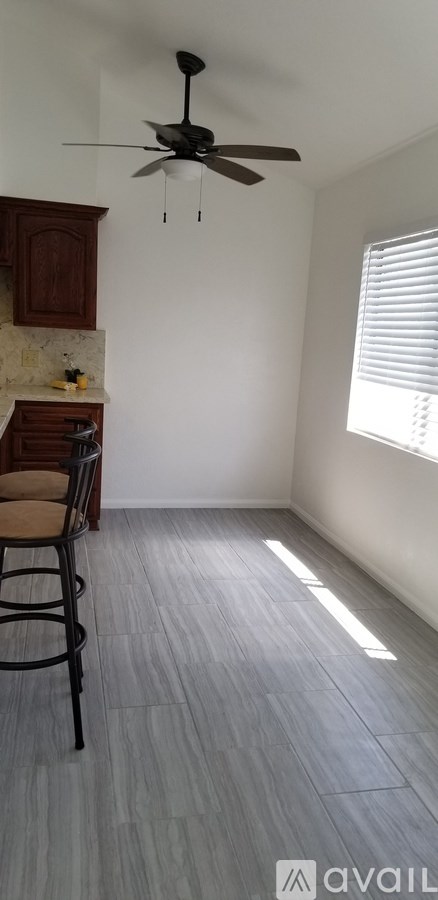 A room with a ceiling fan and wooden flooring.