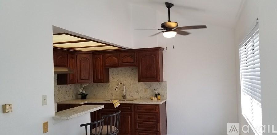 A kitchen with brown cabinets and a ceiling fan.