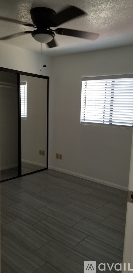 A room with a ceiling fan and a window with blinds.
