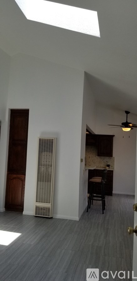 A room with a ceiling fan and a table with a chair.