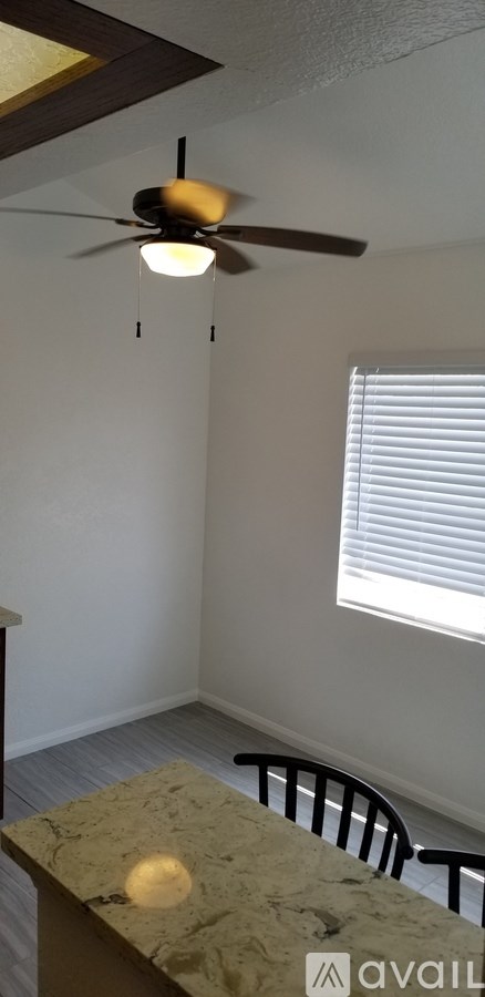 A room with a ceiling fan and a table with a chair.