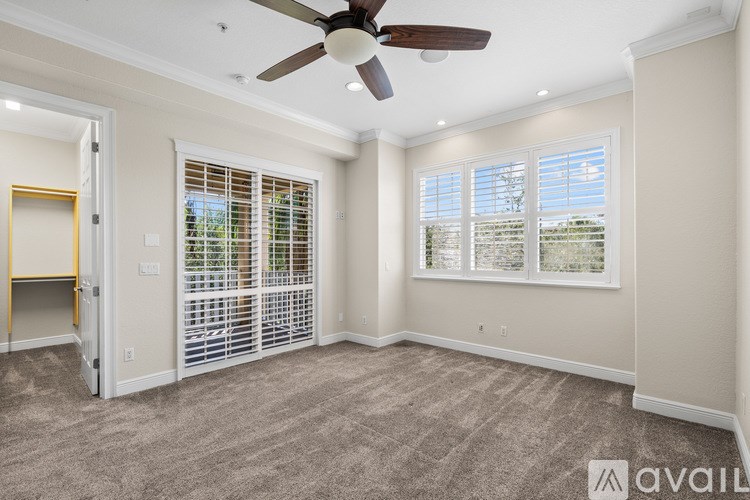 A room with a ceiling fan and a window with blinds.