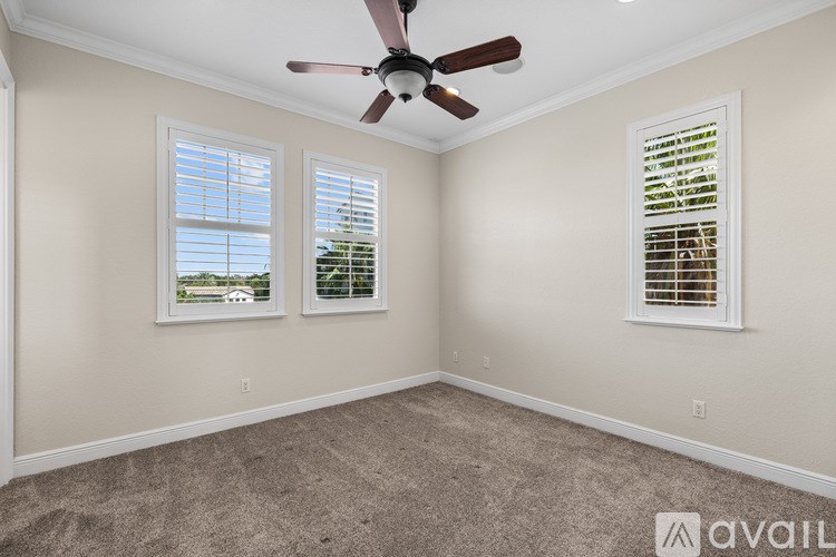 A room with a ceiling fan and two windows with blinds.