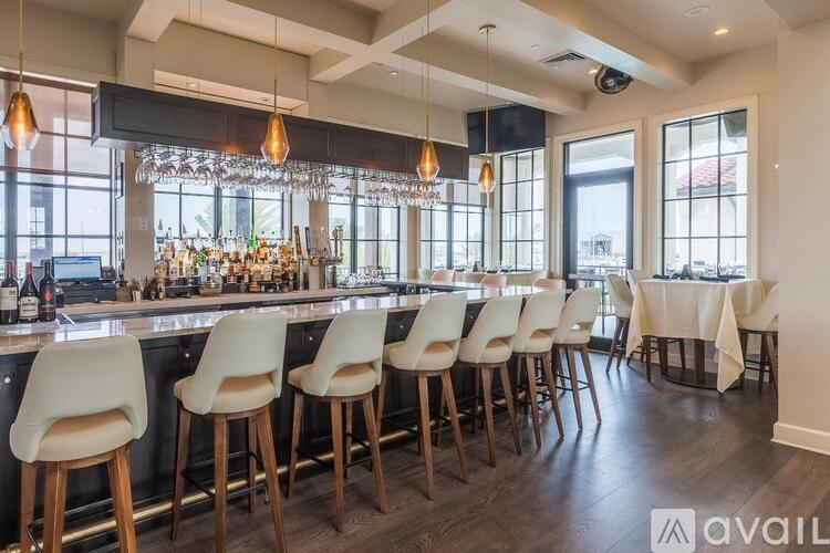 A bar with white chairs and a counter with bottles on it.