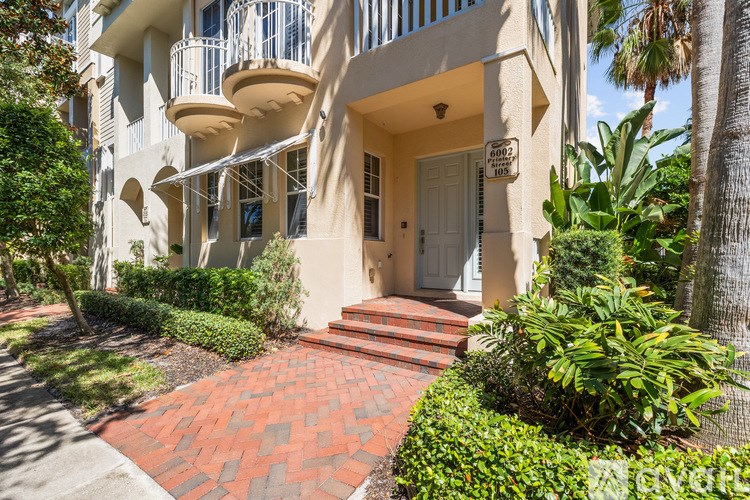 A white building with a red brick walkway in front.