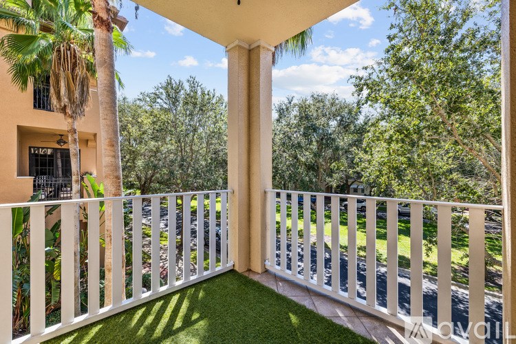 A balcony with a white railing and a view of a road and trees.