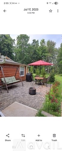 A red umbrella is on a patio with a table and chairs.