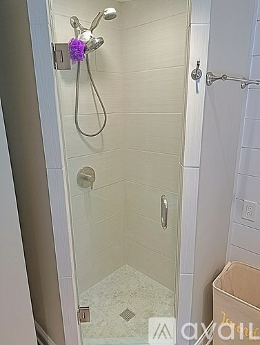 A shower with a purple flower attached to the shower head.