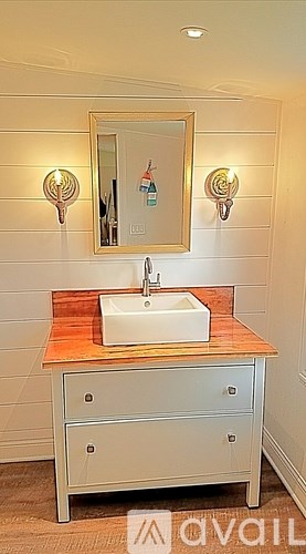 A bathroom with a sink, mirror, and light fixtures.