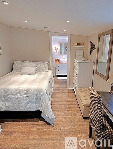 A bedroom with a bed, a chair, and a mirror.