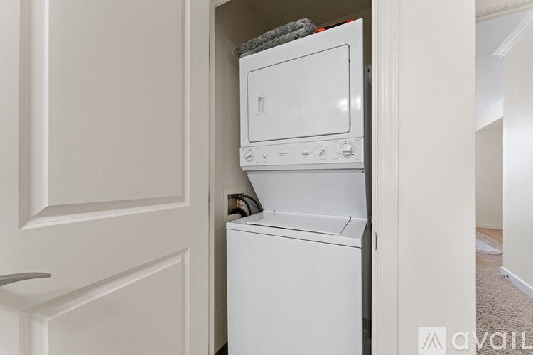 A white dishwasher and microwave are stacked on top of each other in a narrow space.
