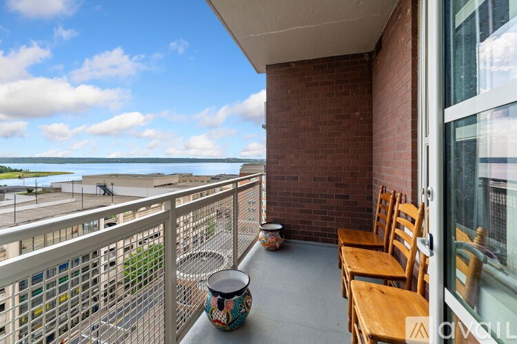 A balcony with a table, chairs and a vase.