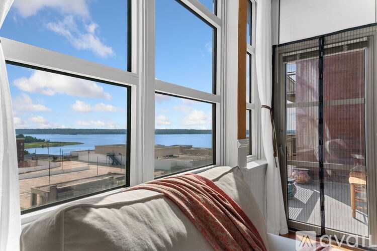 A bedroom with a large window overlooking a waterfront.