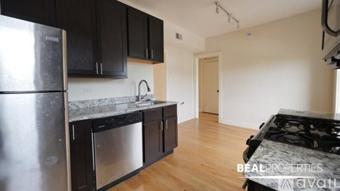 A kitchen with black cabinets and a stainless steel refrigerator.