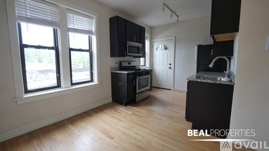 A kitchen with black cabinets and a wooden floor.