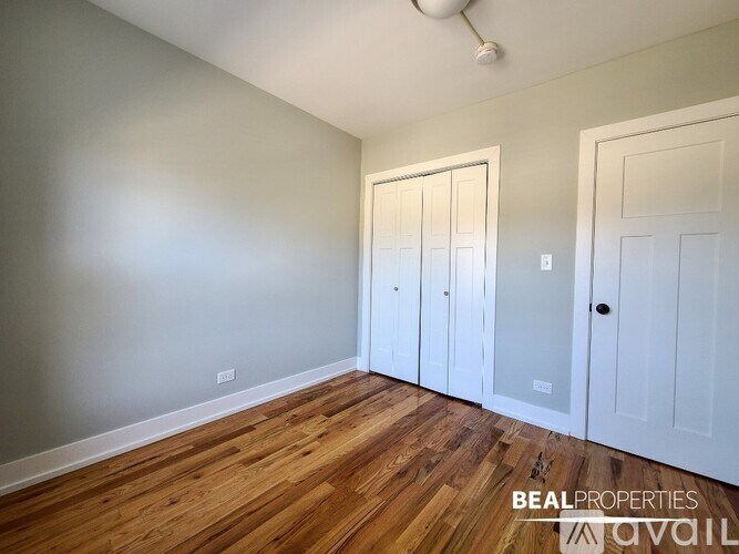 A room with wooden floors and white walls, with two white doors.