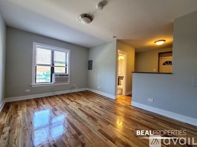 A room with wooden flooring and a window with blinds.