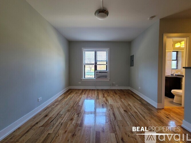 A room with wooden floors and a window with blinds.