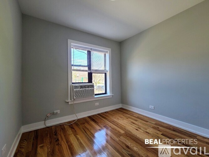 A room with wooden floors and a window with blinds.