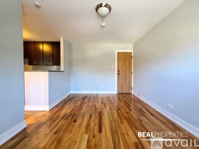 A room with wooden flooring and a door on the right side.