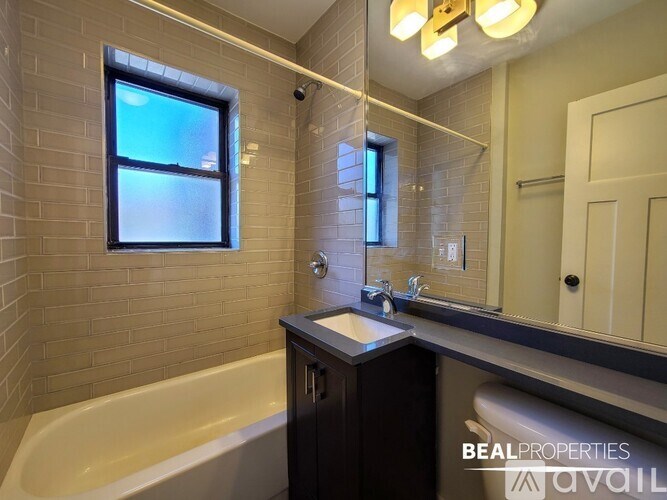 A bathroom with a tub, sink, and mirror.