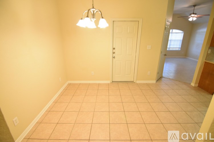 A room with a white door and a chandelier hanging from the ceiling.