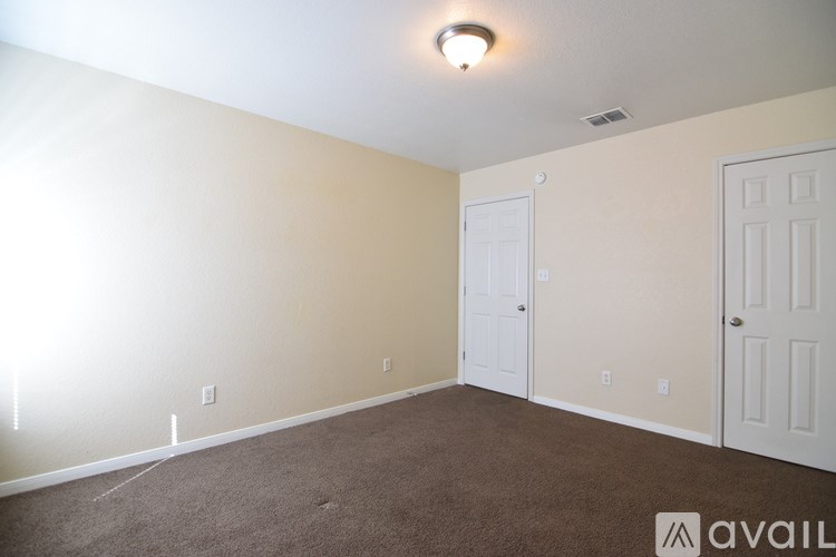 A room with a carpeted floor and a door in the background.