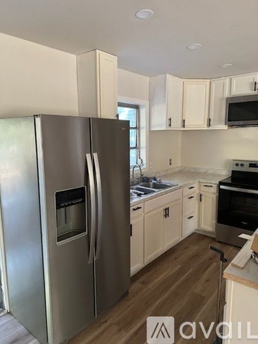 A kitchen with a stainless steel refrigerator and wooden floors.