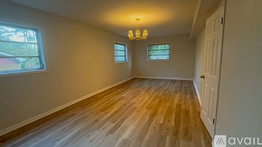 A room with wooden flooring and two windows.