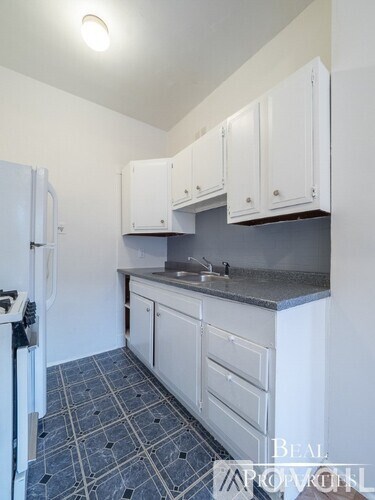 A kitchen with white cabinets and a black fridge.
