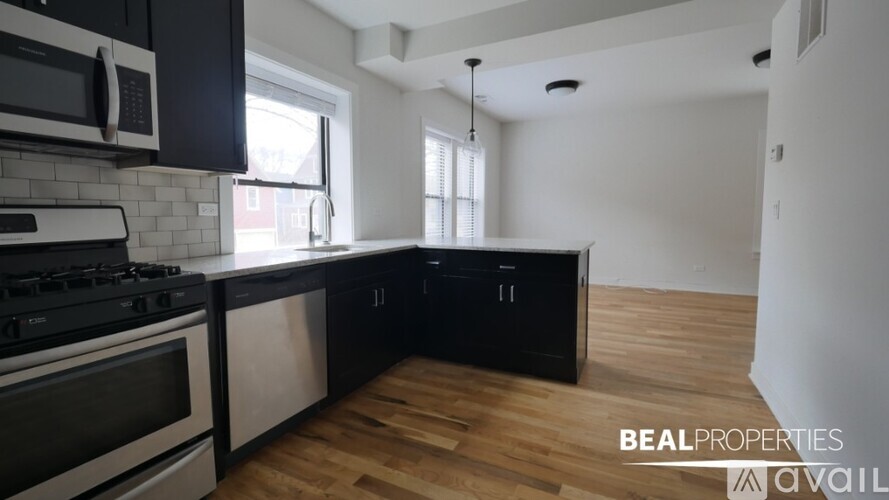 A modern kitchen with black cabinets and stainless steel appliances.
