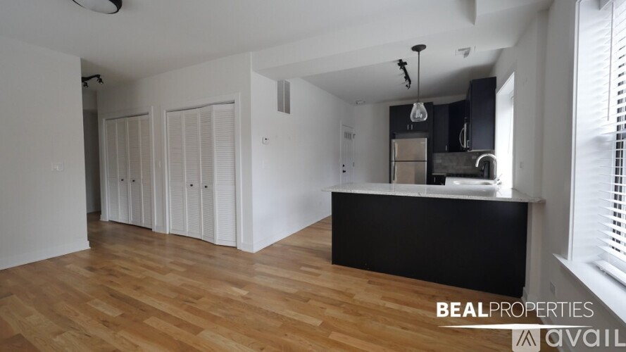 A spacious room with wooden flooring and a black countertop.