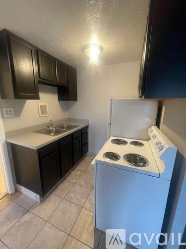 A kitchen with a white stove top oven and black cabinets.