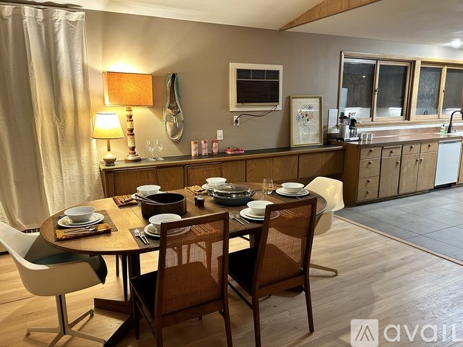A dining room with a table set for four and a kitchen area in the background.