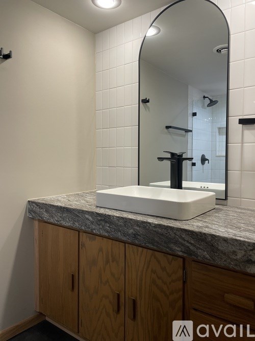 A bathroom with a marble countertop and wooden cabinets.