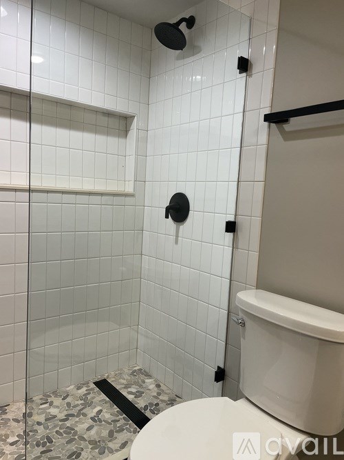 A white toilet in a bathroom with a white tiled shower.